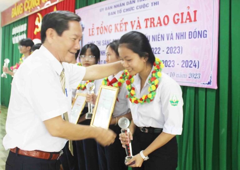 Ông Nguyễn Văn Khoa, Chủ tịch Liên hiệp các hội Khoa học - Kỹ thuật tỉnh trao cúp và giấy chứng nhận giải nhì cho Phạm Bùi Trúc Lam. Ảnh: LỆ VĂN